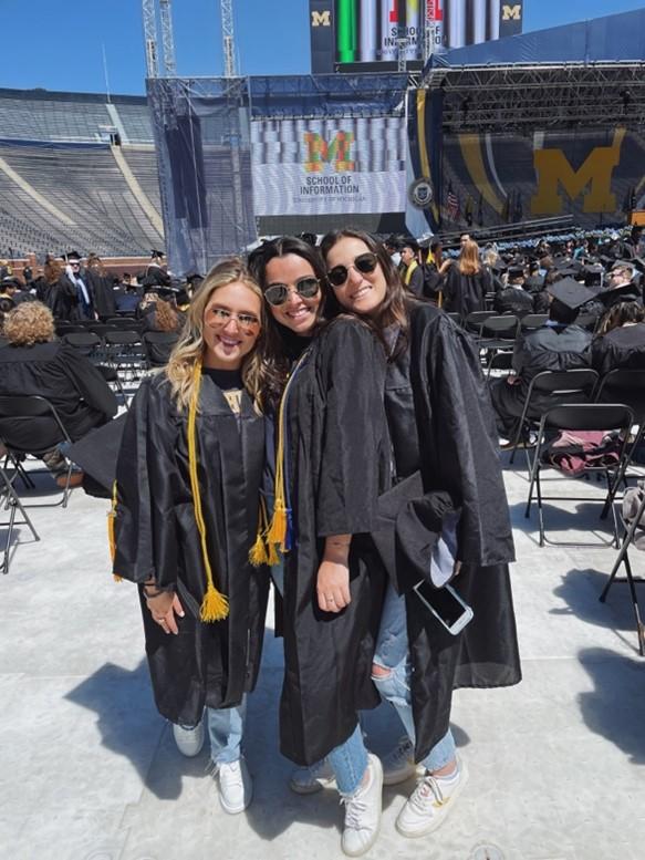 YLC member Hilary smiling at graduation with two friends